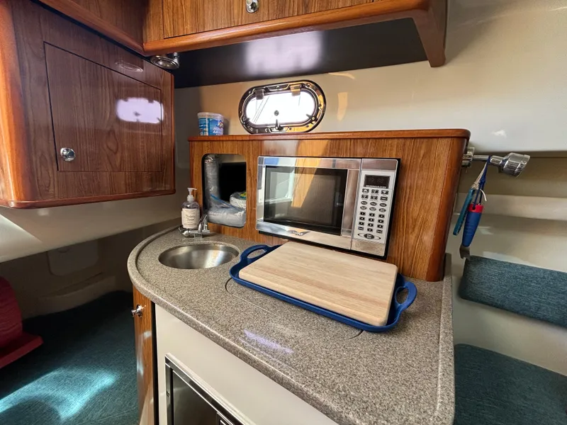 Slide: The Image of 2007 Pursuit 285 Offshore boat interior with kitchenette, microwave, sink, and cutting board. - 20