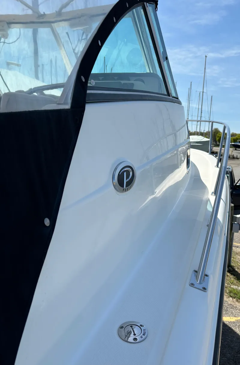 Slide: The Image of 2007 Pursuit 285 Offshore boat, sleek white exterior, docked under clear blue sky. - 5