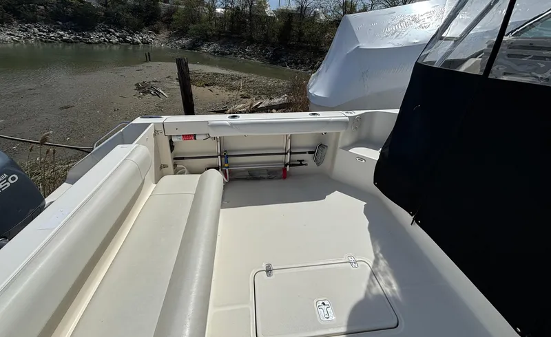 Slide: The Image of 2007 Pursuit 285 Offshore boat deck with seating and storage, near a calm shoreline. - 7