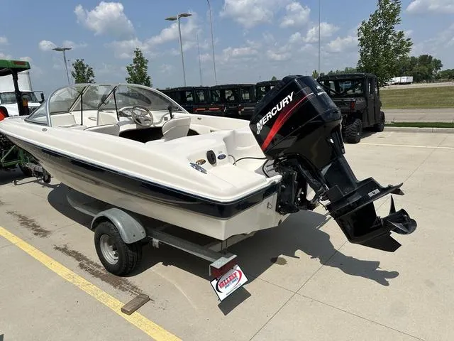 Slide: The Image of 2002 Bayliner 160 Capri boat with Mercury outboard motor on a trailer, parked outdoors. - 11