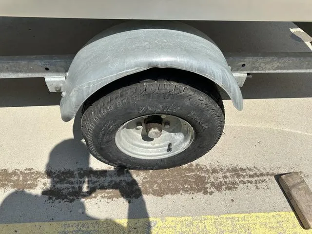 Slide: The Image of Trailer wheel of a 2002 Bayliner 160 Capri boat on concrete surface. - 14