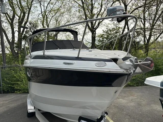 Slide: The Image of 2022 Crownline 264 CR boat, docked, surrounded by trees, front view. - 2