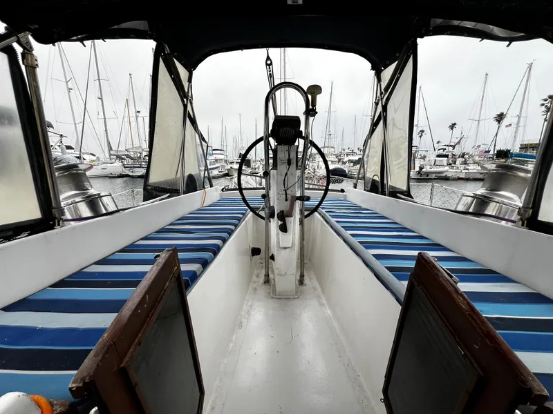 Slide: The Image of 1974 Irwin 37 Center Cockpit sailboat interior with striped seating, docked in marina. - 16