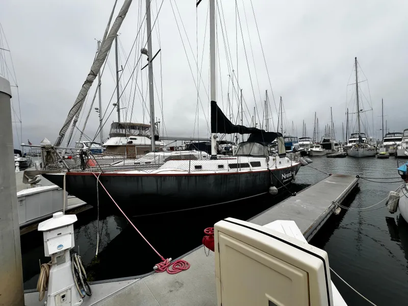 Slide: The Image of 1974 Irwin 37 Center Cockpit sailboat docked at a marina on a cloudy day. - 2