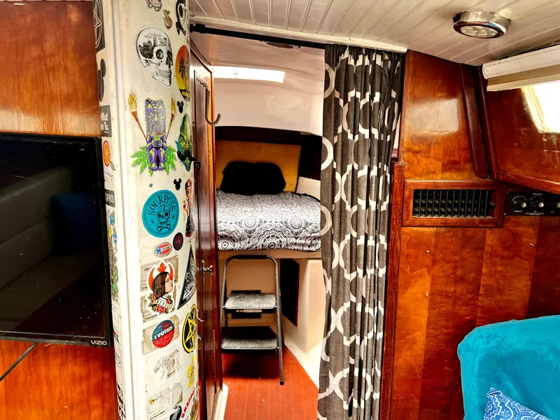Slide: The Image of 1974 Irwin 37 Center Cockpit interior with cozy cabin, decorated wall, and patterned curtain. - 27