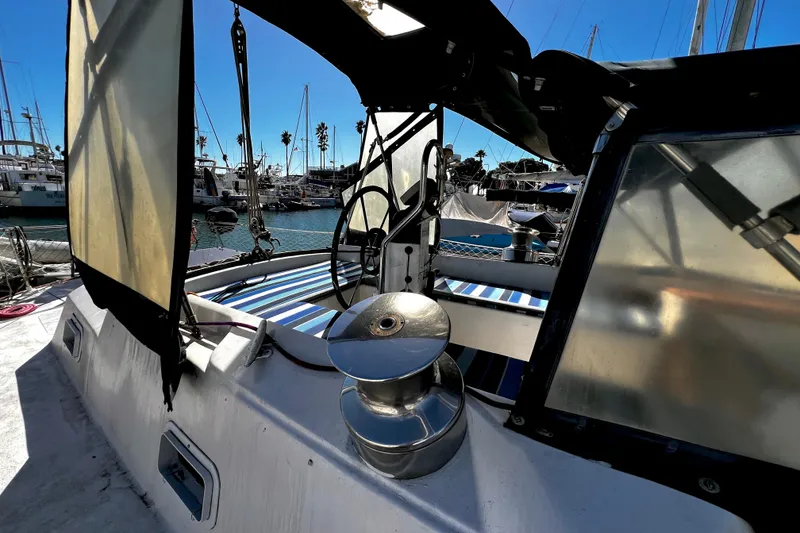 Slide: The Image of 1974 Irwin 37 Center Cockpit sailboat with marina backdrop, featuring helm and winch. - 43