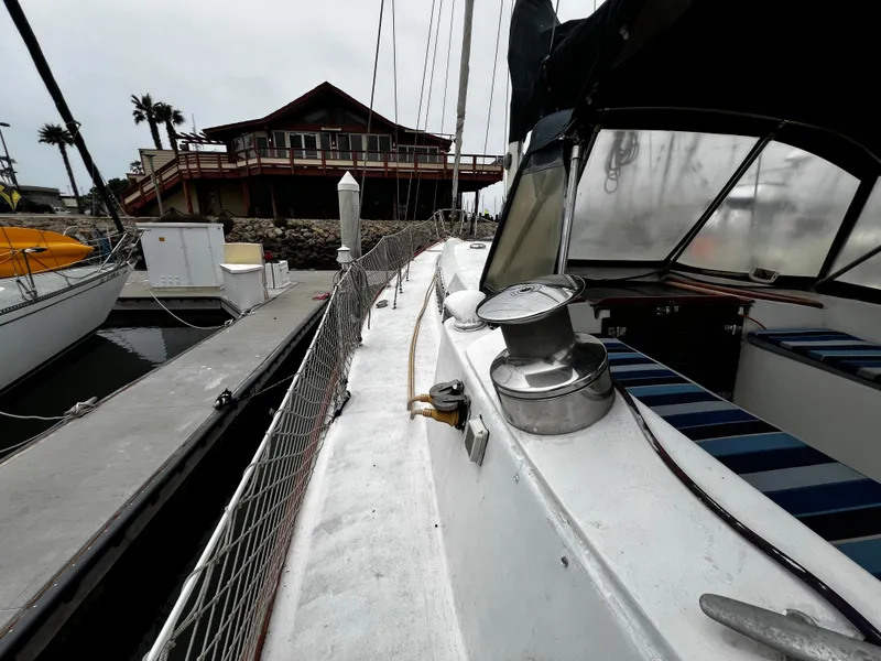Slide: The Image of 1974 Irwin 37 Center Cockpit sailboat docked near a waterfront house. - 6