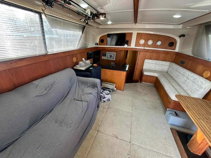 Slide: The Image of 1988 Luhrs Tournament 400 Convertible yacht interior with sofas, TV, and wooden accents. - 8