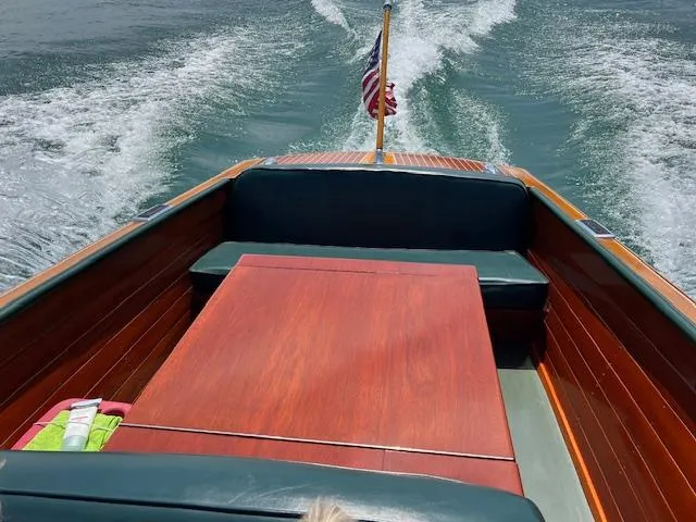 Slide: The Image of 1956 Chris-Craft 23 Continental boat cruising on water, featuring wooden deck and American flag. - 12