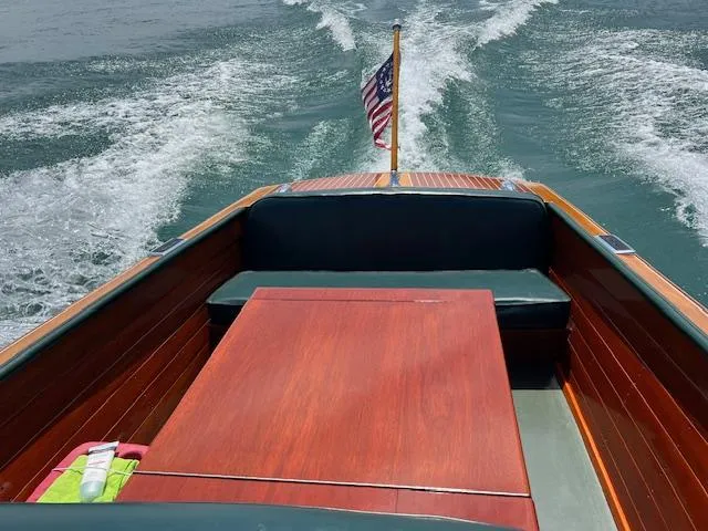 Slide: The Image of 1956 Chris-Craft 23 Continental boat with wooden deck and American flag on water. - 13