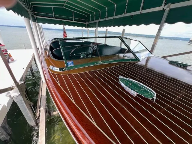 Slide: The Image of 1956 Chris-Craft 23 Continental boat with polished wooden deck under a canopy by the lake. - 31