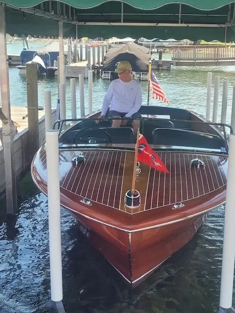 Slide: The Image of 1956 Chris-Craft 23 Continental boat docked, featuring classic wooden design and American flag. - 36