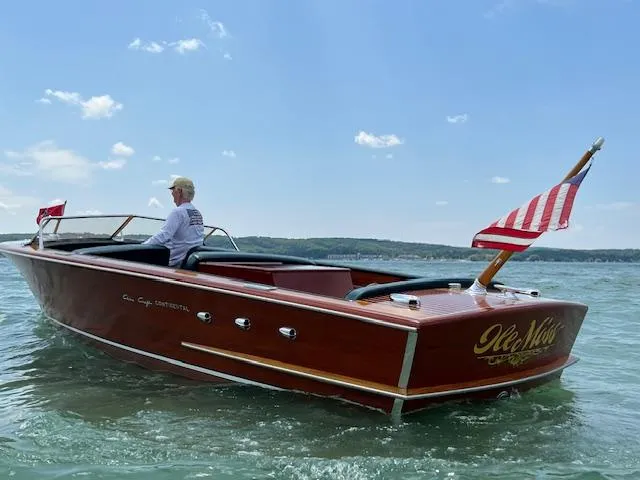 Slide: The Image of 1956 Chris-Craft 23 Continental boat on water, American flag, clear sky. - 4