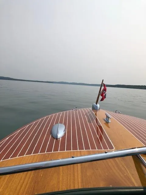 Slide: The Image of 1956 Chris-Craft 23 Continental boat on calm water, showcasing classic wooden deck design. - 7