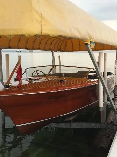 Slide: The Image of 1956 Chris-Craft 23 Continental wooden boat docked under a yellow canopy. - 9