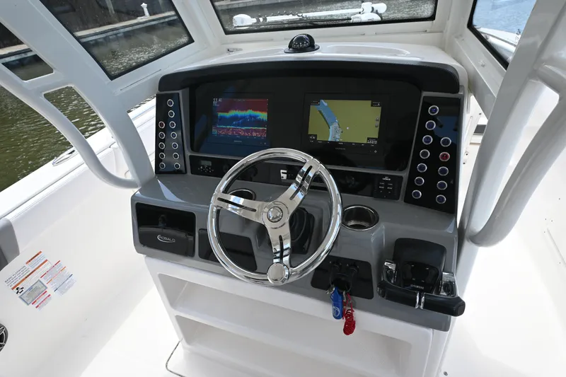 Slide: The Image of 2020 Robalo R272 Center Console boat dashboard with navigation screens and steering wheel. - 5