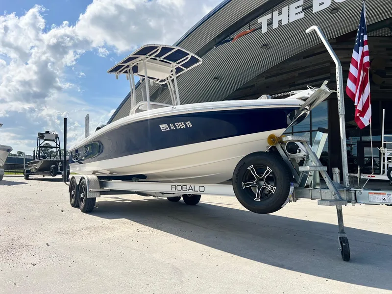 Slide: The Image of 2022 Robalo 206 Cayman boat on trailer, parked outside dealership under blue sky. - 10