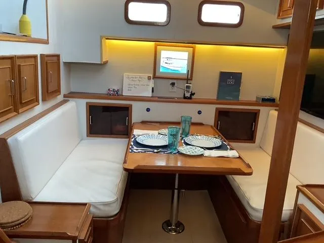 Slide: The Image of 1988 Jefferson 42 Sundeck interior with dining area, wooden cabinetry, and cozy seating. - 1