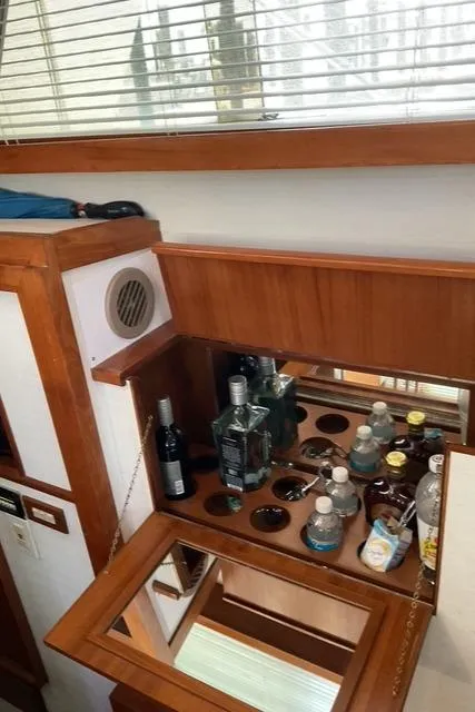 Slide: The Image of 1988 Jefferson 42 Sundeck interior bar with assorted beverages and wooden cabinetry. - 33