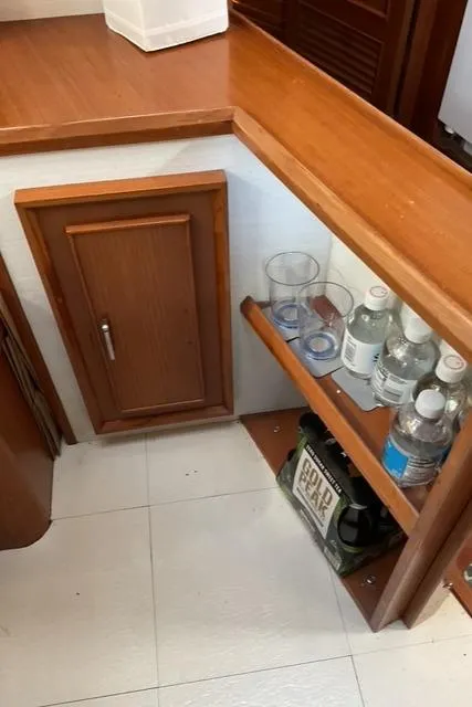 Slide: The Image of 1988 Jefferson 42 Sundeck interior with wooden cabinet and shelf holding bottles and glasses. - 41