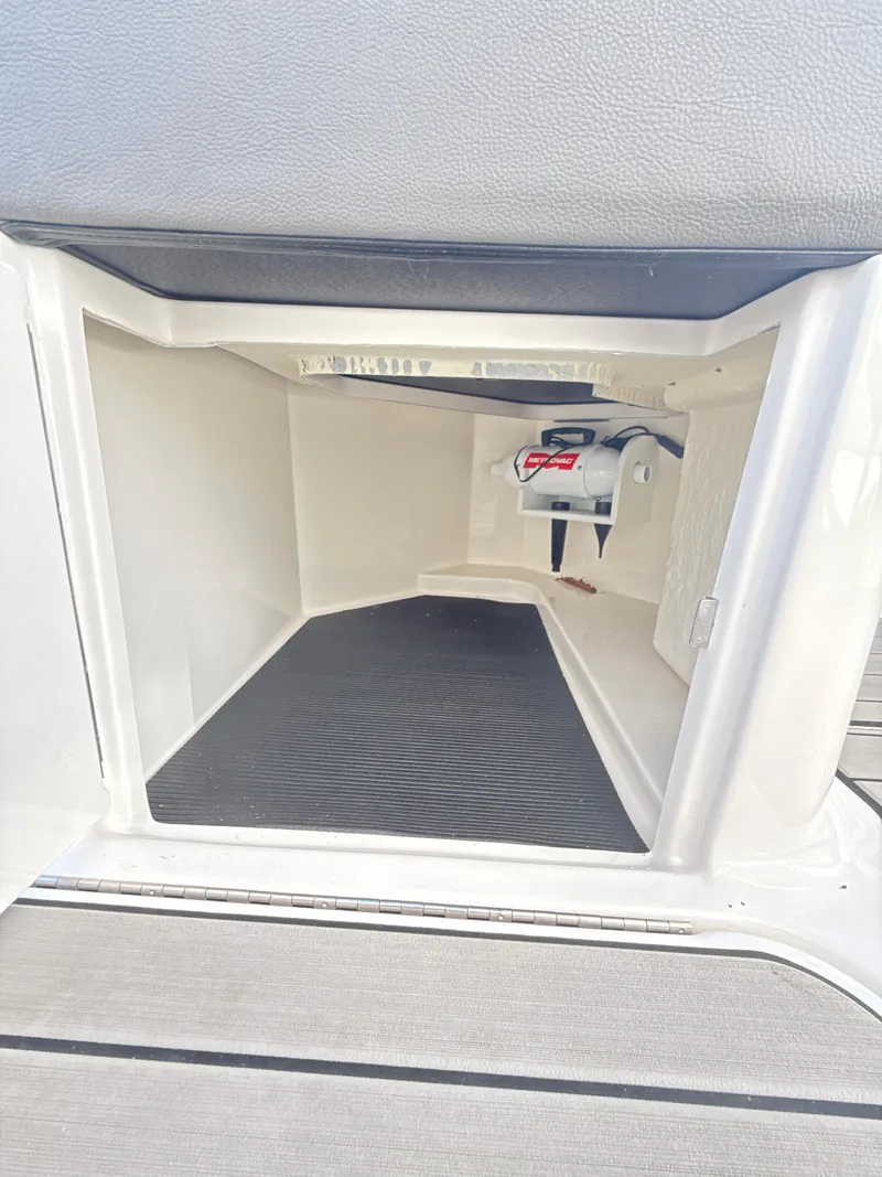 Slide: The Image of 2023 Sea Ray SLX 310 OB storage compartment with black mat and battery switch. - 23