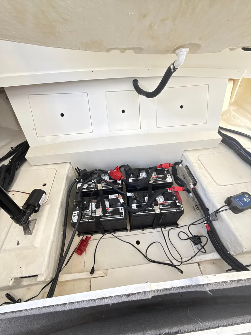 Slide: The Image of 2023 Sea Ray SLX 310 OB boat battery compartment with multiple batteries and wiring. - 28