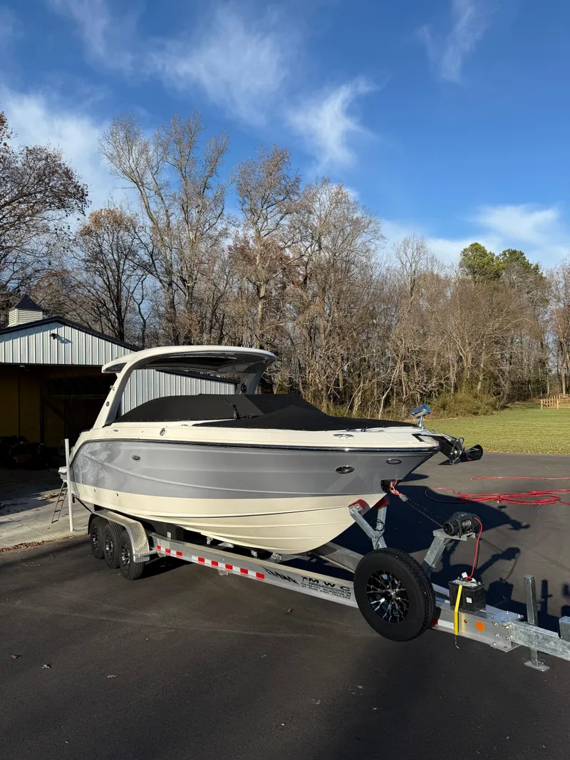Slide: The Image of 2023 Sea Ray SLX 310 OB boat on trailer, parked outdoors under clear sky. - 46