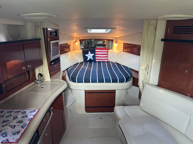 Slide: The Image of 2004 Sea Ray 320 Sundancer cabin interior with bed, kitchenette, and seating area. - 11