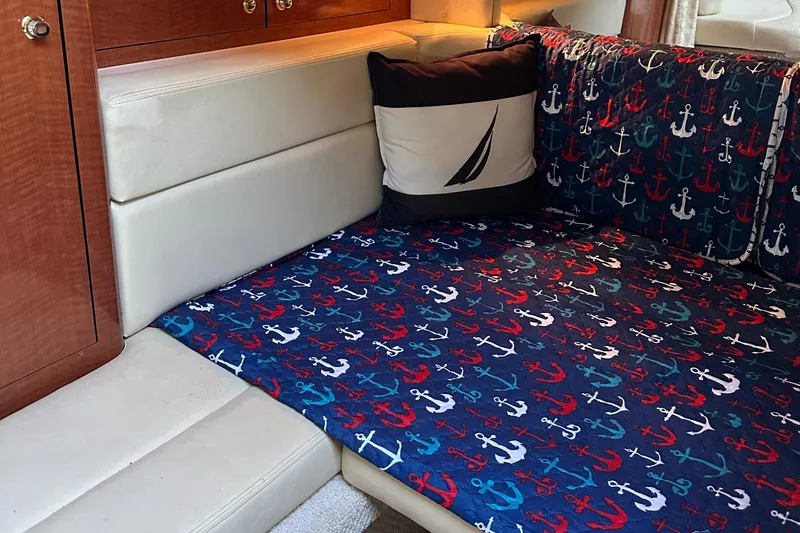 Slide: The Image of 2004 Sea Ray 320 Sundancer cabin with nautical-themed bedding and anchor patterns. - 15
