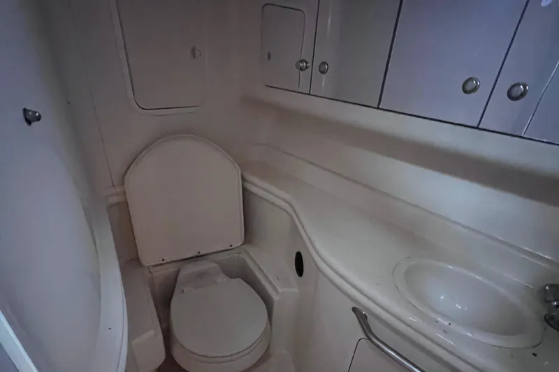 Slide: The Image of 2004 Sea Ray 320 Sundancer bathroom with toilet, sink, and storage cabinets. - 17