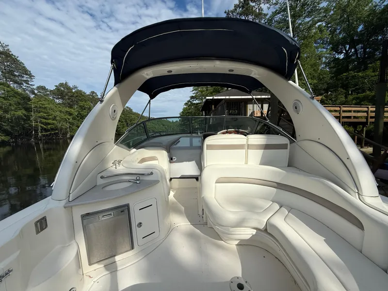 Slide: The Image of 2004 Sea Ray 320 Sundancer boat interior with seating and canopy on a calm waterway. - 3