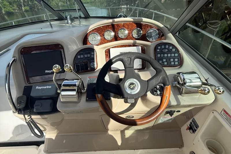 Slide: The Image of 2004 Sea Ray 320 Sundancer helm with steering wheel, gauges, and navigation controls. - 7
