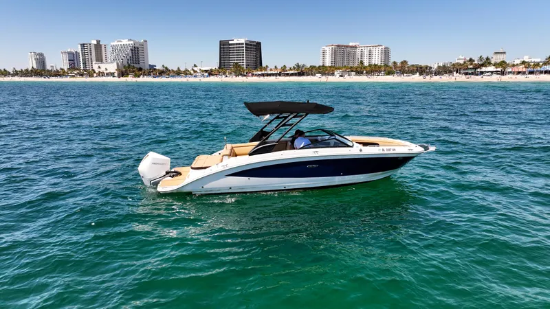 Slide: The Image of 2021 Sea Ray SDX 270 boat cruising on clear blue water near a city skyline. - 1