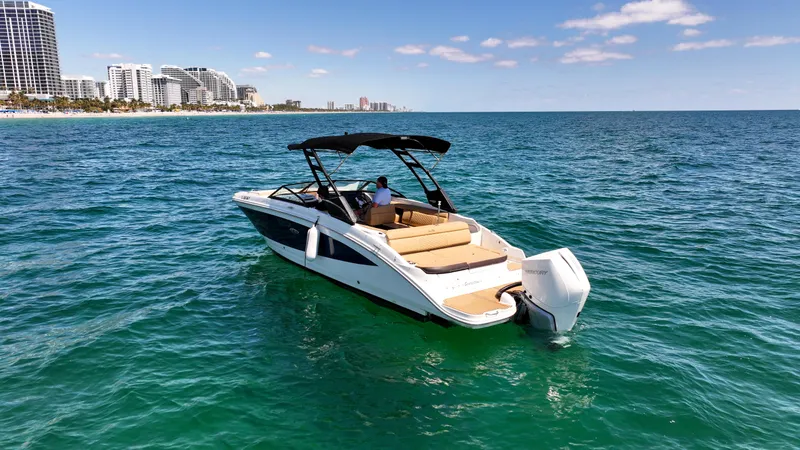Slide: The Image of 2021 Sea Ray SDX 270 boat cruising on clear blue ocean near city skyline. - 4