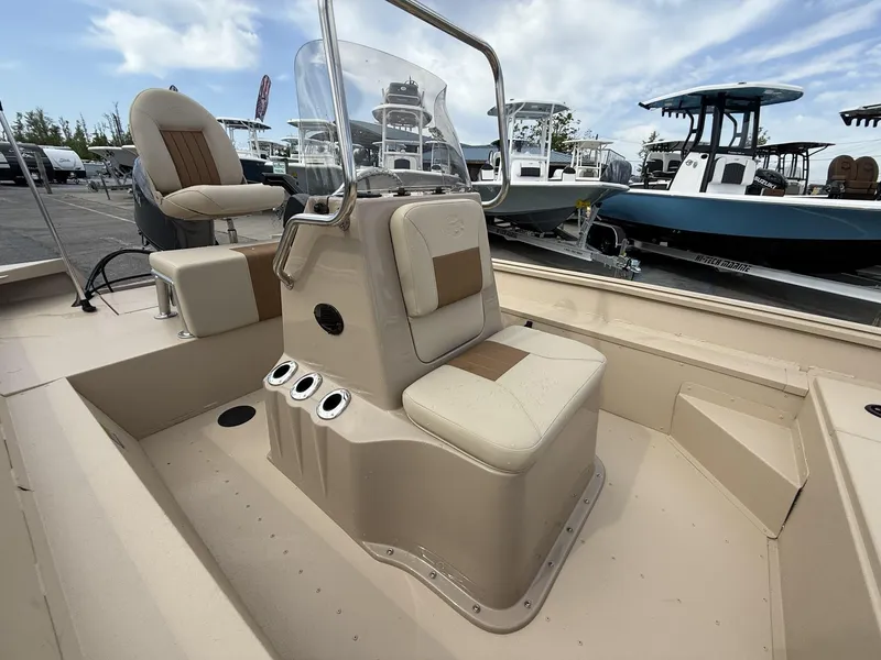 Slide: The Image of 2025 G3 Bay 17 boat interior with beige seating and console, parked at a marina. - 11
