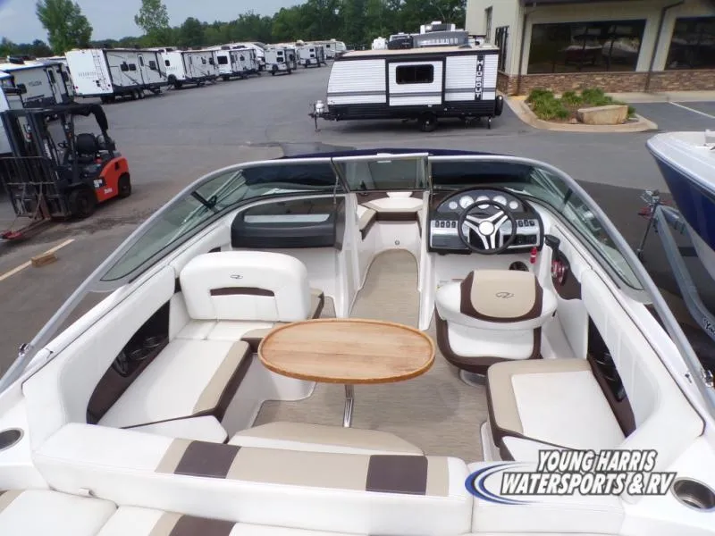 Slide: The Image of 2017 Regal 2000 ES boat interior with seating and table, parked near RVs. - 6