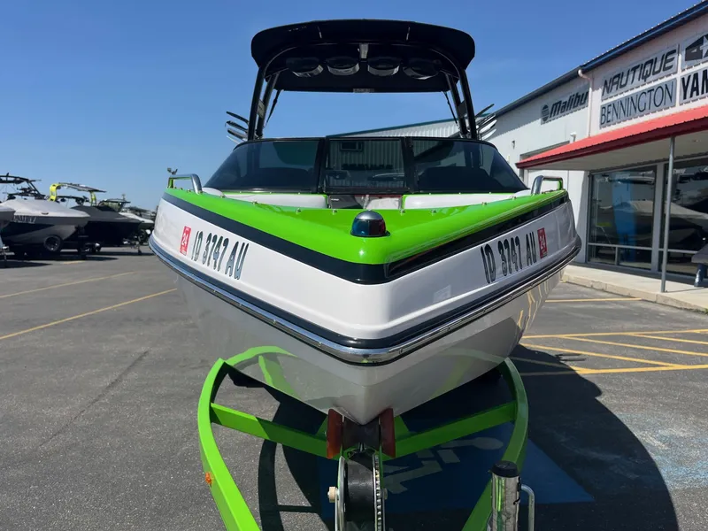 Slide: The Image of 2014 Moomba Mobius LSV boat in vibrant green and white, parked at a dealership. - 11
