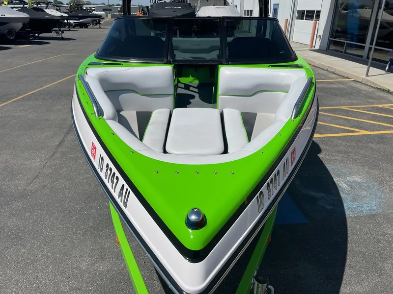 Slide: The Image of 2014 Moomba Mobius LSV boat with vibrant green and white seating, parked outdoors. - 13