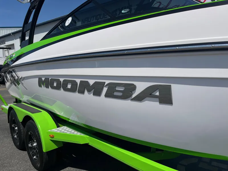 Slide: The Image of 2014 Moomba Mobius LSV boat with green accents on a trailer. - 15