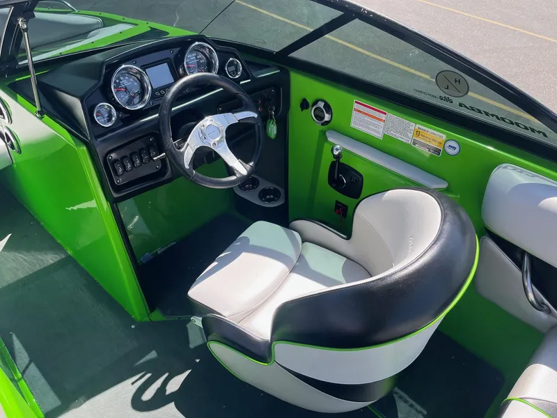 Slide: The Image of 2014 Moomba Mobius LSV boat interior with green accents and modern dashboard. - 26