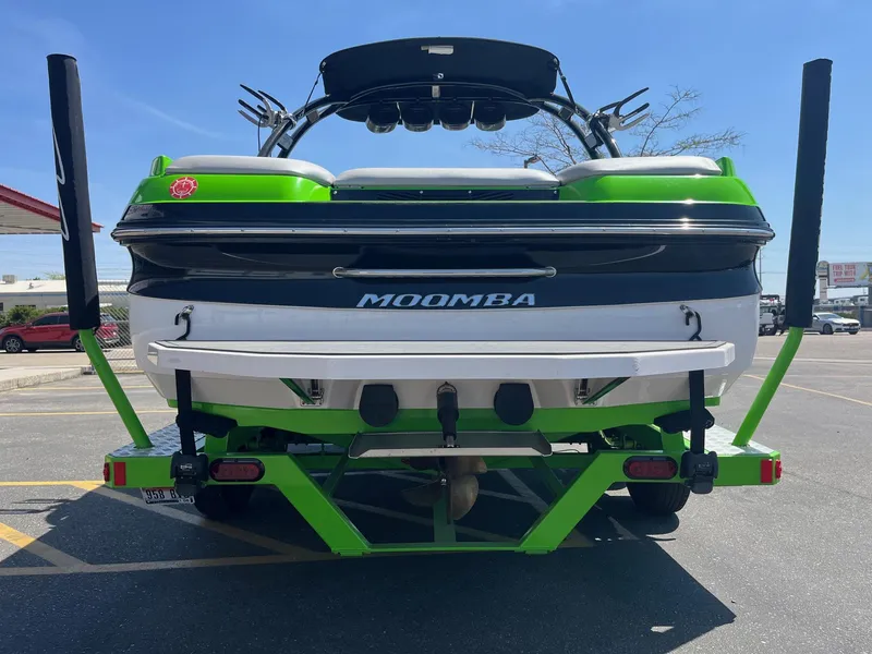 Slide: The Image of 2014 Moomba Mobius LSV boat, green and white, parked on a trailer in a lot. - 5