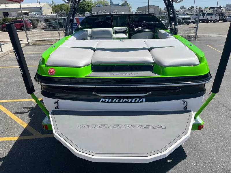 Slide: The Image of 2014 Moomba Mobius LSV boat with green accents, rear view in a parking lot. - 7