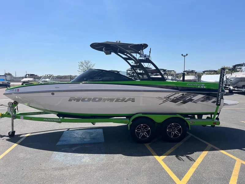Slide: The Image of 2014 Moomba Mobius LSV boat on trailer, green and white design, parked in marina lot. - 9