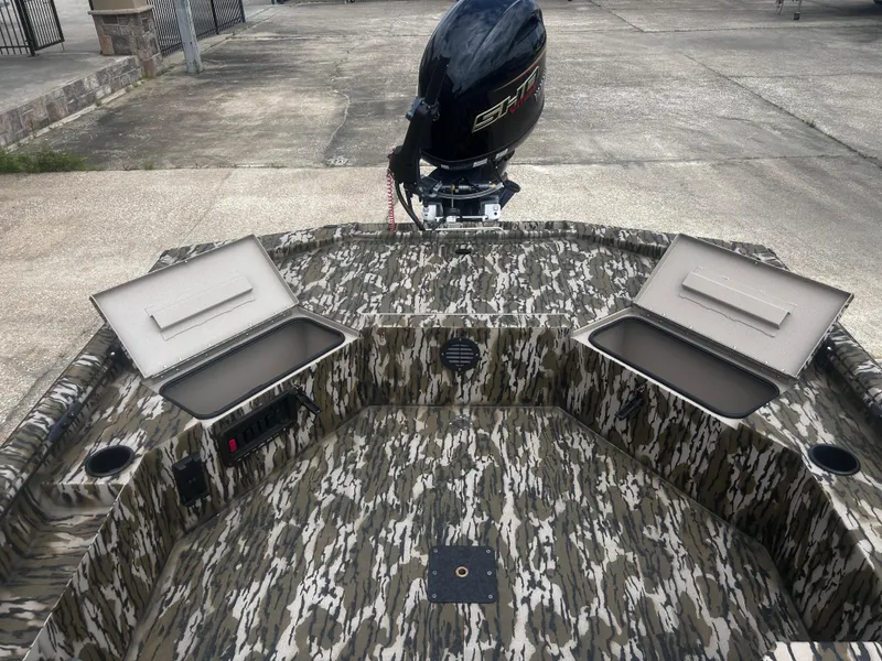 Slide: The Image of 2025 Avid 18 Commander boat with camo design and open storage compartments. - 12