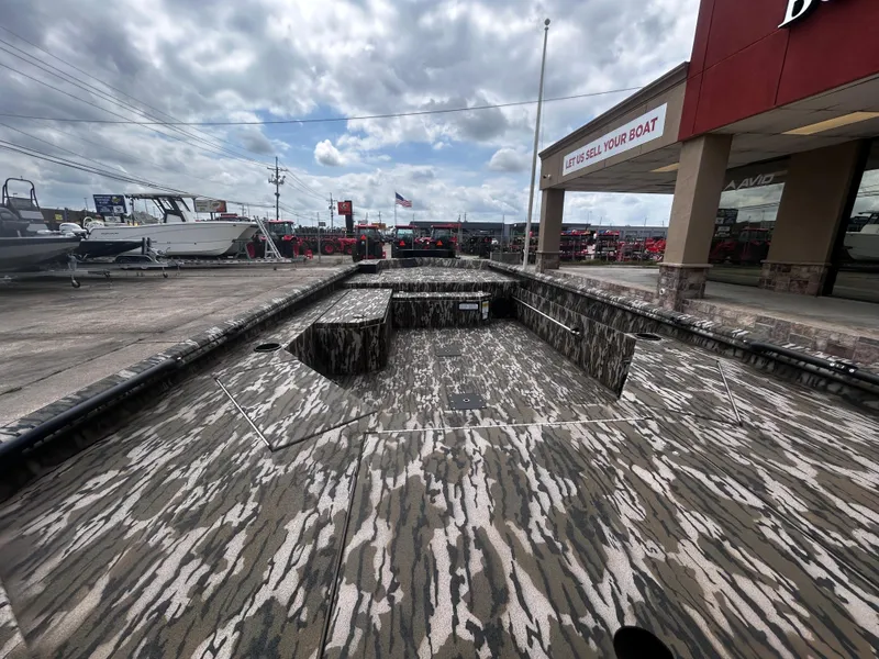 Slide: The Image of 2025 Avid 18 Commander boat with camouflage design at dealership under cloudy sky. - 9