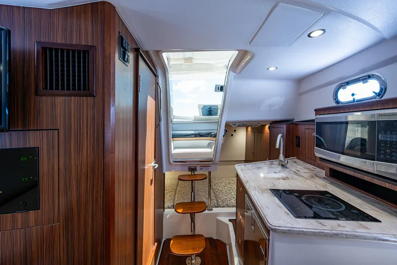 Slide: The Image of Interior of 2017 Pursuit 325 OS boat with kitchen and seating area. - 10