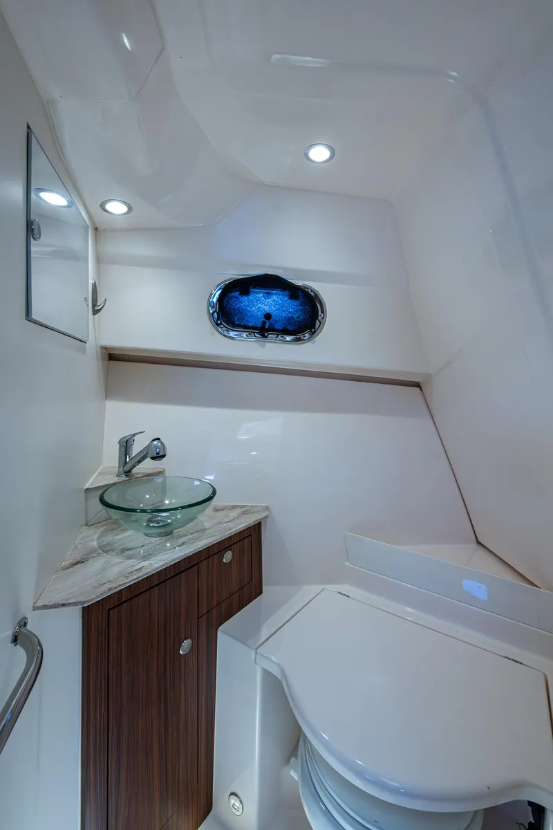Slide: The Image of 2017 Pursuit 325 OS boat bathroom with modern fixtures and porthole window. - 13