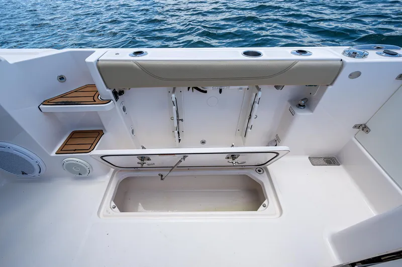 Slide: The Image of 2017 Pursuit 325 OS boat interior with storage compartment and seating, on calm water. - 17