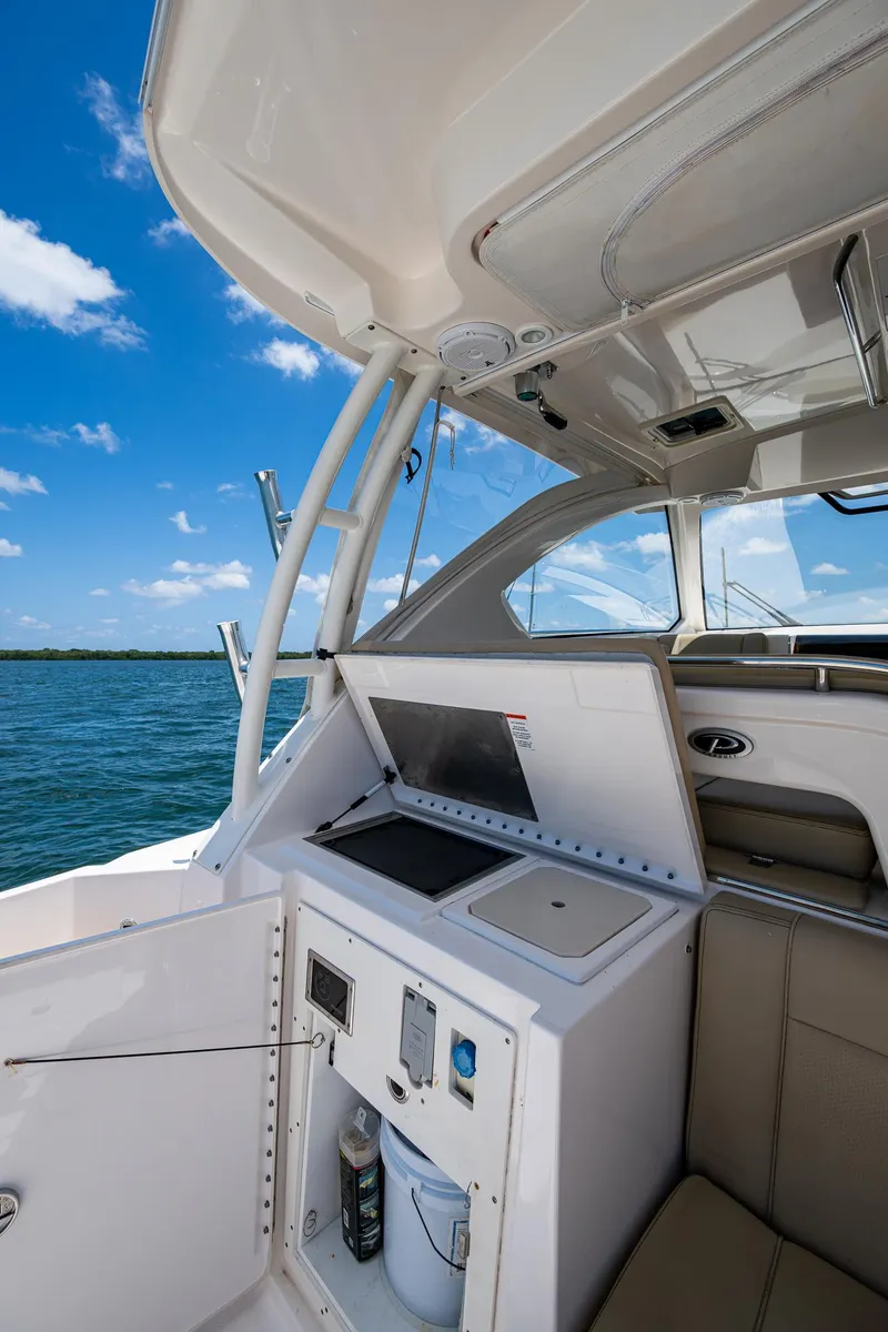 Slide: The Image of 2017 Pursuit 325 OS boat interior with open hatch, ocean view, and clear blue sky. - 20