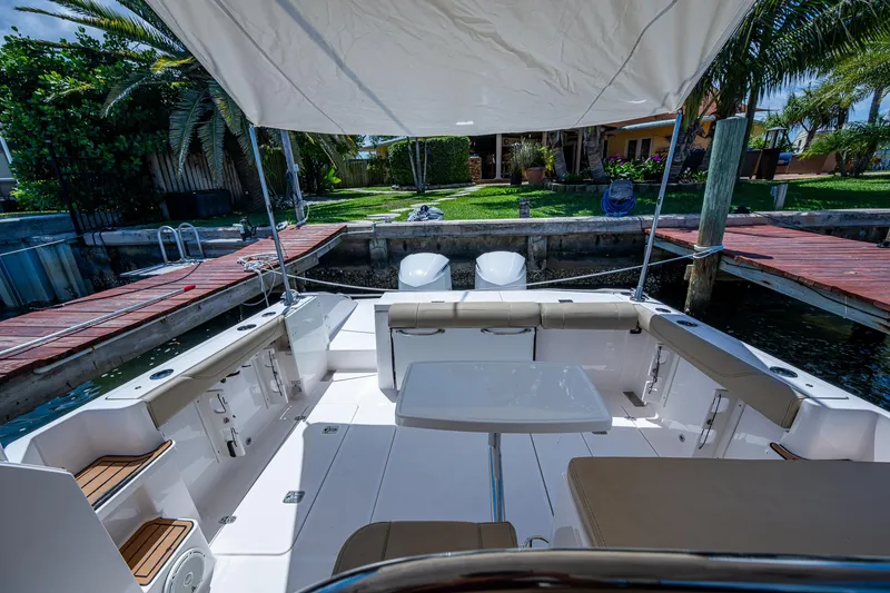 Slide: The Image of 2017 Pursuit 325 OS boat interior with seating, table, and canopy in a dock setting. - 22